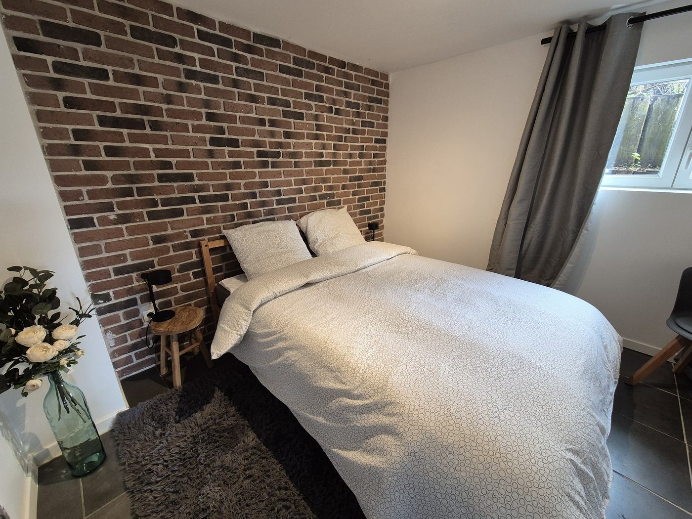 Chambre du Loft des Cigognes avec mur en briques et grand lit