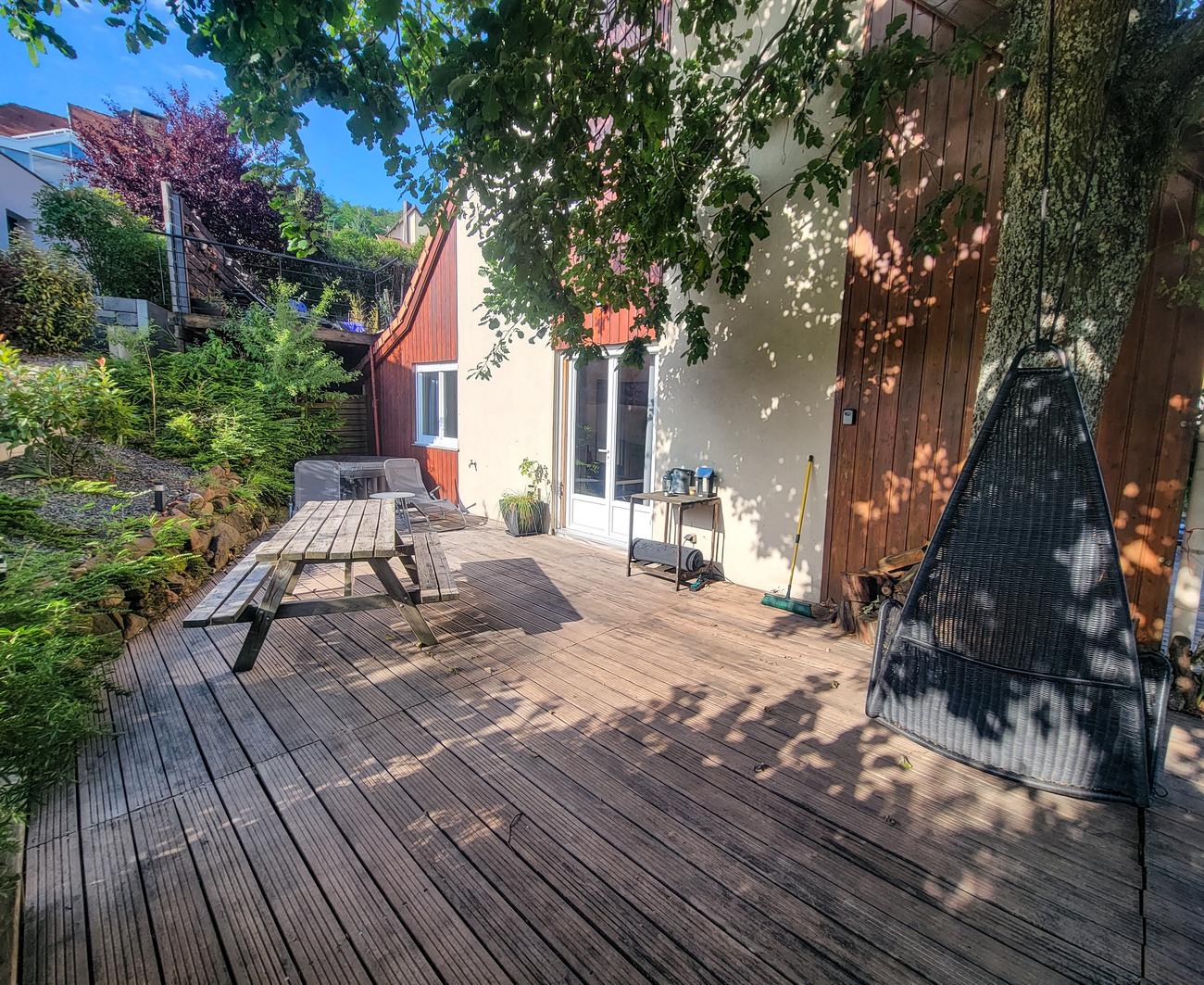 Terrasse privée de 60 m² avec table, transats et fauteuil suspendu